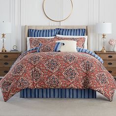 a bed in a bedroom with red and blue comforter set on top of it