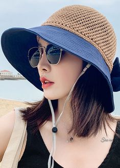 a woman wearing a hat and sunglasses on the beach