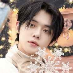 a young man with black hair holding a snowflake