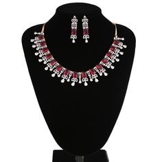 American Diamond bridal collar choker necklace studded with ruby red and clear CZ stones encrusted on rose gold background. Necklace comes with a pair of matching earrings. This is very unique and beautiful Indian Necklace set studded high quality AD stones beautifully decorated work. Stone shape: emerald cut and Pear Necklace Length: 9 inches+ Length of Extender is 9 inches Earring Length: 1.75 inches Contents: 1 Necklace, 2 Earrings Best suitable for Party Wear / Fashion Wear for Any Occasion. Elegant Red Rhinestone Necklaces, Red Diamond Necklace For Festive Occasions, Red Diamond Necklace For Party, Red Bridal Necklace With Sparkling Stones For Wedding, Festive Red Diamond Necklace, Red Rhinestone Wedding Jewelry, Red Crystal Necklaces For Celebrations, Rose Gold Ruby Jewelry For Parties, Elegant Red Choker Jewelry Sets