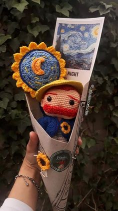 someone is holding up a crocheted doll in the shape of a sunflower