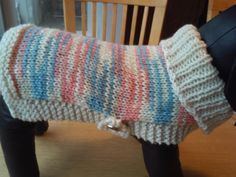 a dog is wearing a sweater made out of knitted yarn and sits on a chair