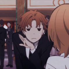 an anime scene with two people in suits and one is holding his hand to his face