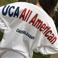 "UCA all American across the shoulders of this oversized jersey shirt and cheerleader in smaller letters under that line. This one has the British flag with name and year but it's your choice. Add matching bow! These run HUGE! The XS is about 42\" chest, S 44\" and so on. Order accordingly. Long sleeve, ring-spun cotton tshirt. Super soft . Please specify your lettering and colors allow 7-10 days processing."