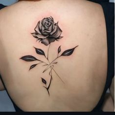 a woman's back with a rose tattoo on it