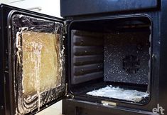 an open black oven with some white stuff in it's door and snow on the inside