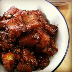 a white bowl filled with meat on top of a wooden table