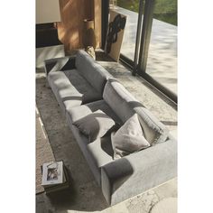 a grey couch sitting on top of a floor next to a window