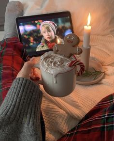 a person sitting on a bed next to a laptop with a gingerbread drink in front of them