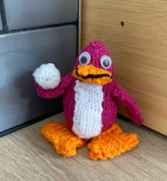 a crocheted penguin sitting next to a door