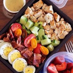 a tray filled with different types of food next to a fork and glass of orange juice