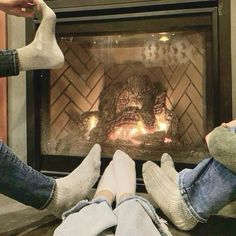 two people sitting in front of a fireplace with their feet up