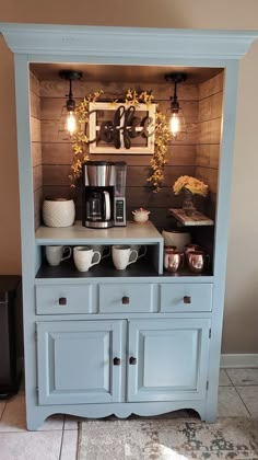 a blue hutch with coffee maker and cups on it's side, sitting in front of a brown wall