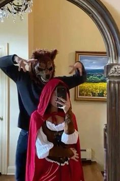 a man in a costume taking a selfie with a woman dressed as a devil