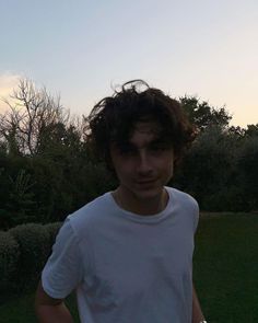 a young man in a white shirt is holding a frisbee and looking at the camera