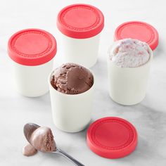 ice cream in plastic containers with spoons on the side and red lids next to them