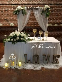 a white table topped with flowers and candles next to a sign that says love on it