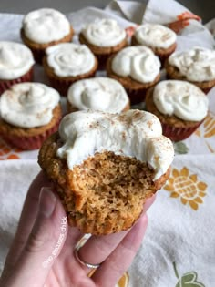 a person holding up a cupcake with frosting on it