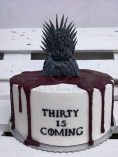 a game of throne cake sitting on top of a white bench