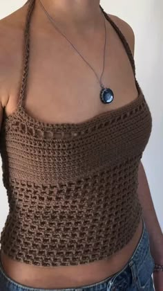 a woman wearing a brown crochet top and necklace