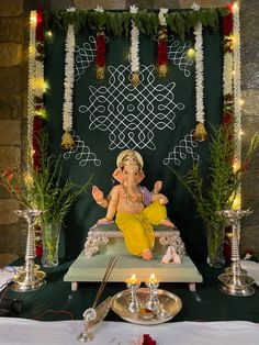 there is an idol sitting on the table with candles in front of it and decorations around it