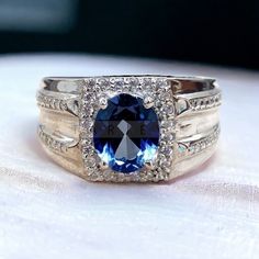 a blue and white diamond ring sitting on top of a table