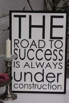 a sign that says the road to success is always under construction next to a candle