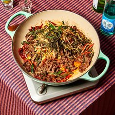 a pan filled with meat and vegetables sitting on top of a table next to bottles of water