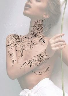 a woman with tattoos on her chest holding a flower in front of her back shoulder