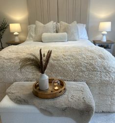 a bedroom with a white bed and two lamps on the nightstands next to it