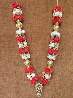 a red and white necklace with flowers on the front, gold beads in the back