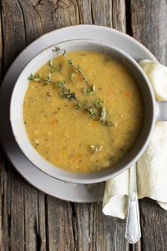 a white bowl filled with soup sitting on top of a wooden table next to a napkin