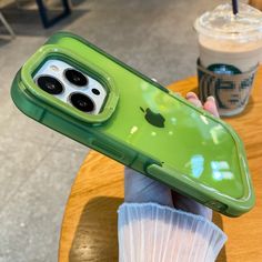 a person holding up an iphone case in front of a cup of coffee on a table