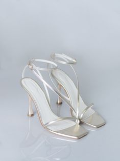 a pair of white high heeled shoes with straps