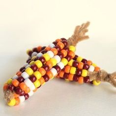 a corn cob made out of candy sits on a white surface with brown, yellow and orange beads