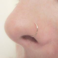 a close up of a person with a nose ring on their nose, looking to the side