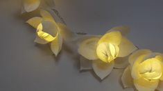 some yellow flowers are lit up on a white wall with lights in the shape of petals