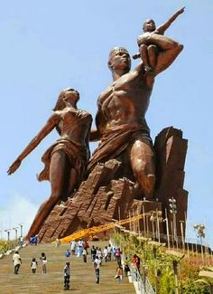 people are walking up and down the stairs to a statue that is on top of a hill