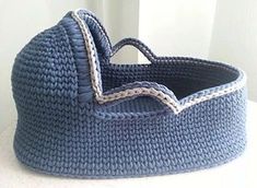 a crocheted blue basket with handles on a white countertop next to a window