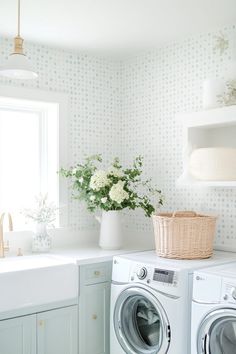 a washer and dryer in a small room next to a window with flowers