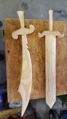 two wooden swords are on display in a workshop, one is carved and the other is made out of plywood