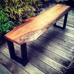 a wooden bench sitting on top of a wooden deck next to bushes and shrubbery