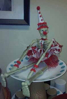 a skeleton sitting on top of a white plate wearing a red and white party hat