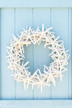 a starfish wreath is hanging on the side of a blue wooden door with white paint