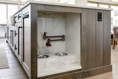 an open cabinet in the middle of a kitchen with stainless steel sinks and faucets