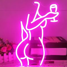 a neon sign that is on top of a table next to some books and flowers