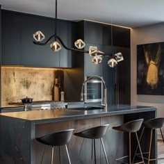 a modern kitchen with black cabinets and stainless steel counter tops, bar stools and pendant lights