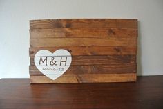 a wooden box with a heart and initials on the front is sitting on a table