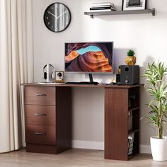 a desk with a computer monitor on top of it next to a potted plant