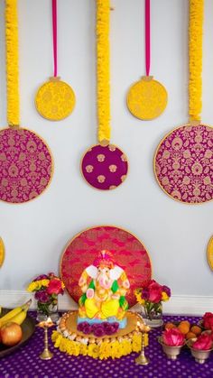 there is a small ganeshi decoration on the wall next to fruit and flowers